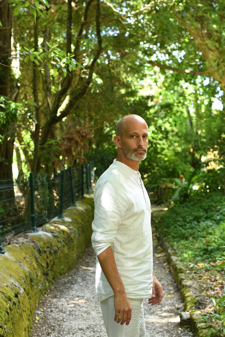 Lior seated in meditation beside a river in a natural setting
